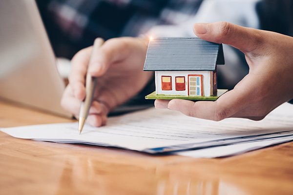 Close up of hand signing contract with house model