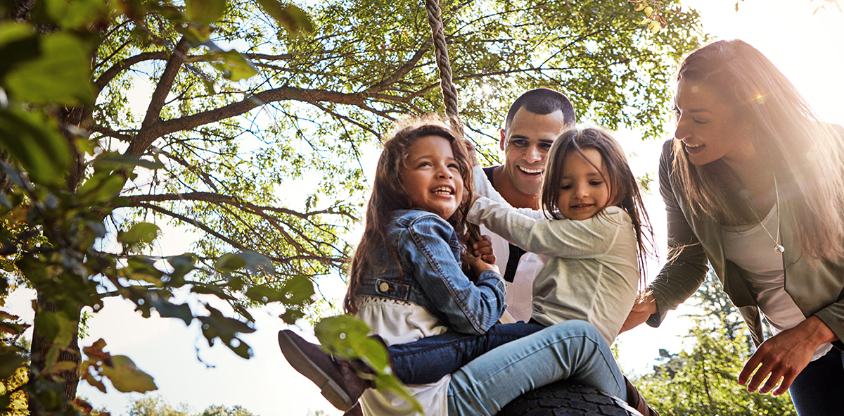 Family playing on tire swing in summer