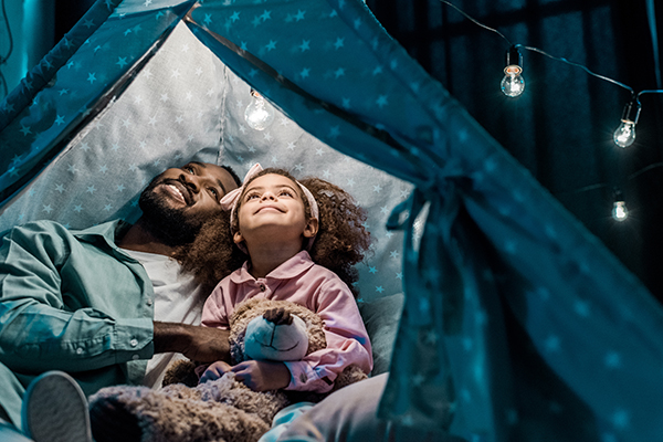Father and daughter admiring the stars in a tent