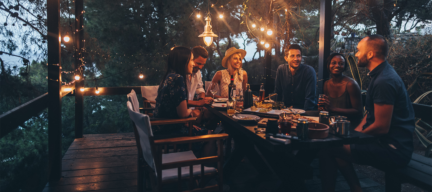 Friends enjoying a dinner party on a deck at night