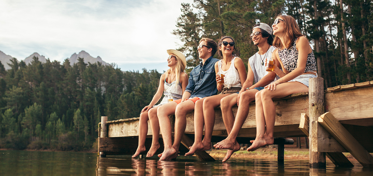 Friends sitting on a dock at the lake in summer