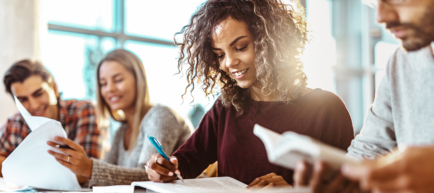 Happy college student studying with classmates