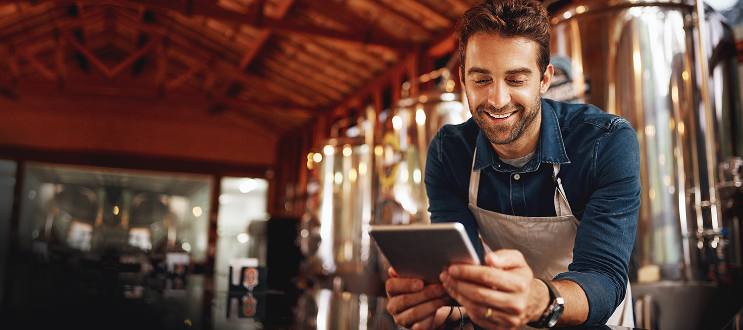 Man in brewery checking banking on iPad